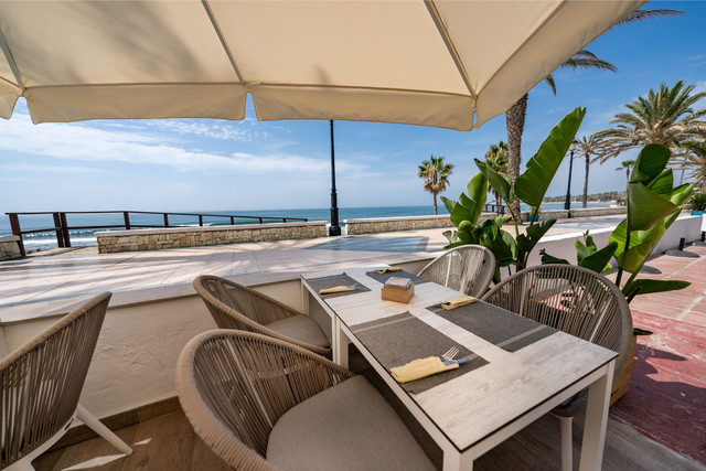 Beachfront restaurant terrace along Marbella&rsquo;s Golden Mile boulevard, showcasing luxury lifestyle near prime properties for sale.
