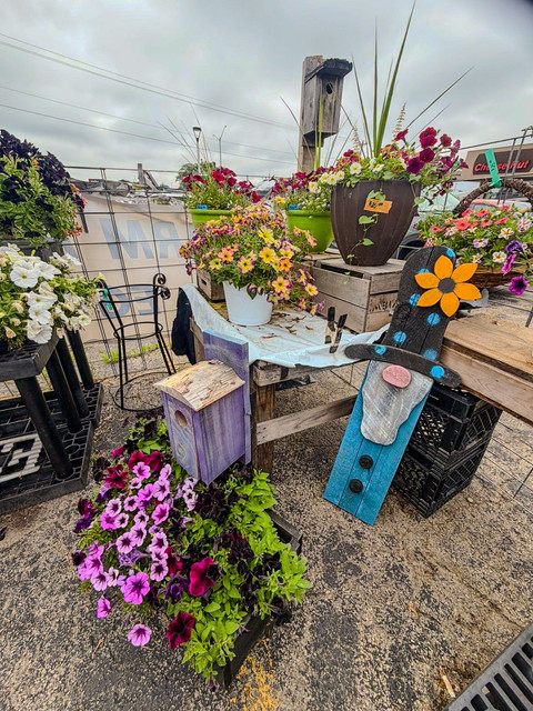 Flower display with garden decorations at DJ's Fresh Market farm stand in Appleton