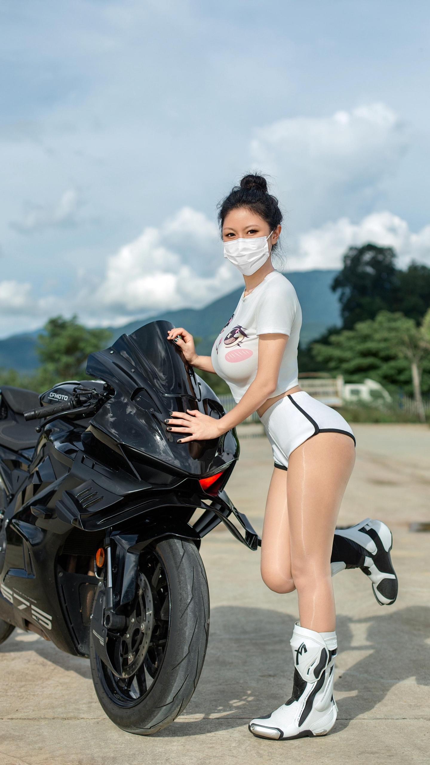 người phụ nữ xinh đẹp đeo mặt nạ Đứng cạnh xe máy và chụp ảnh