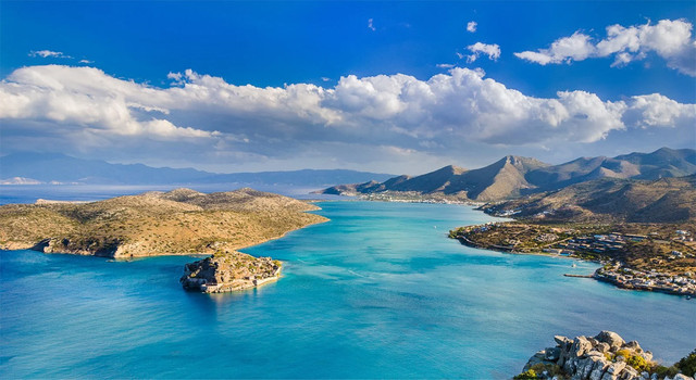 Panoramic view of Elounda, Crete with luxury waterfront resorts, yachts, and turquoise waters — top things to do and real estate opportunities for international buyers in 2025-26 with Destinations by LeadingRE.