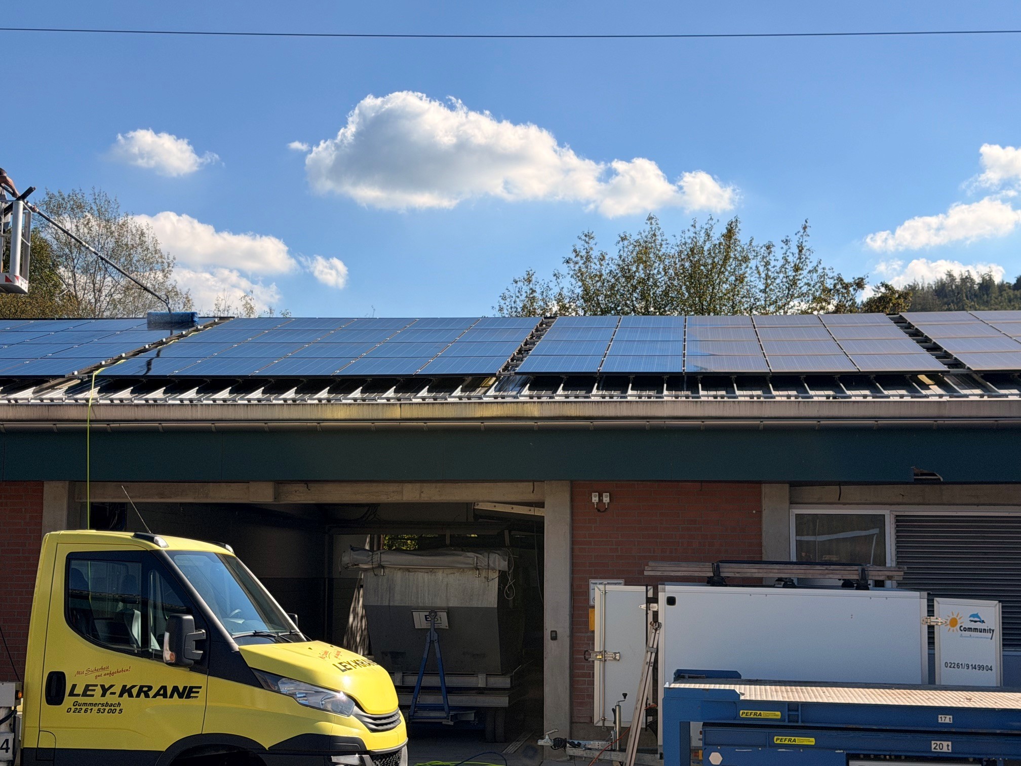 PV-Reinigung auf der Kläranlage des ESI Entsorgungsbetriebs der Stadt Siegen von der Hubarbeitsbühne – links bereits gereinigte, tiefblaue Module, rechts noch verschmutzt