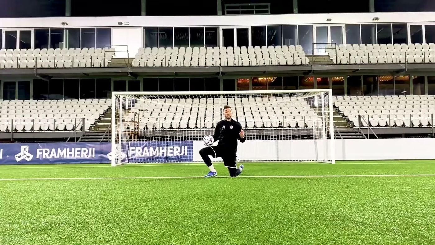 Goalkeeper crouched in his goal in an empty stadium, still and focused