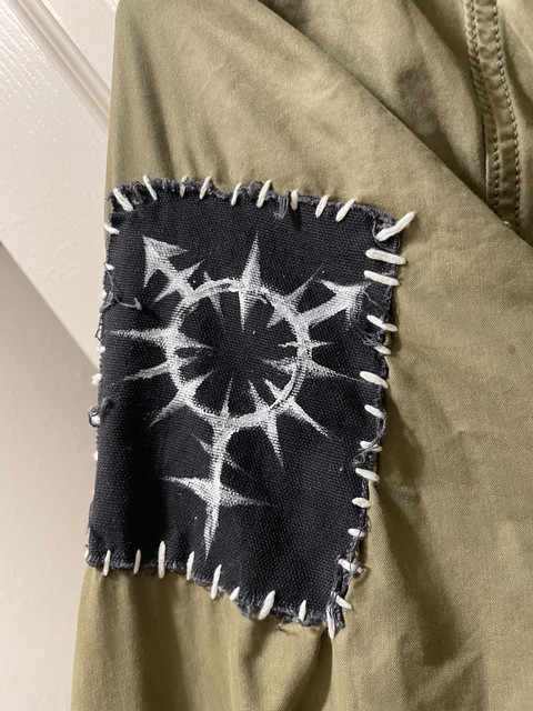 closeup of a patch depicting a spiky stylized trans symbol