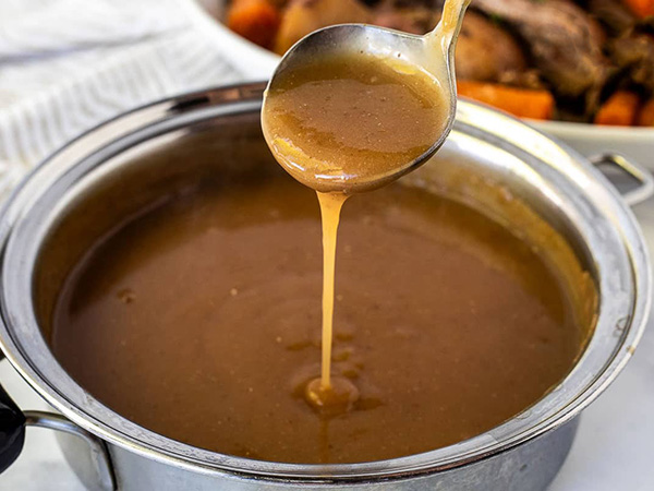 Rich beef gravy displayed in glass container showing luxurious consistency