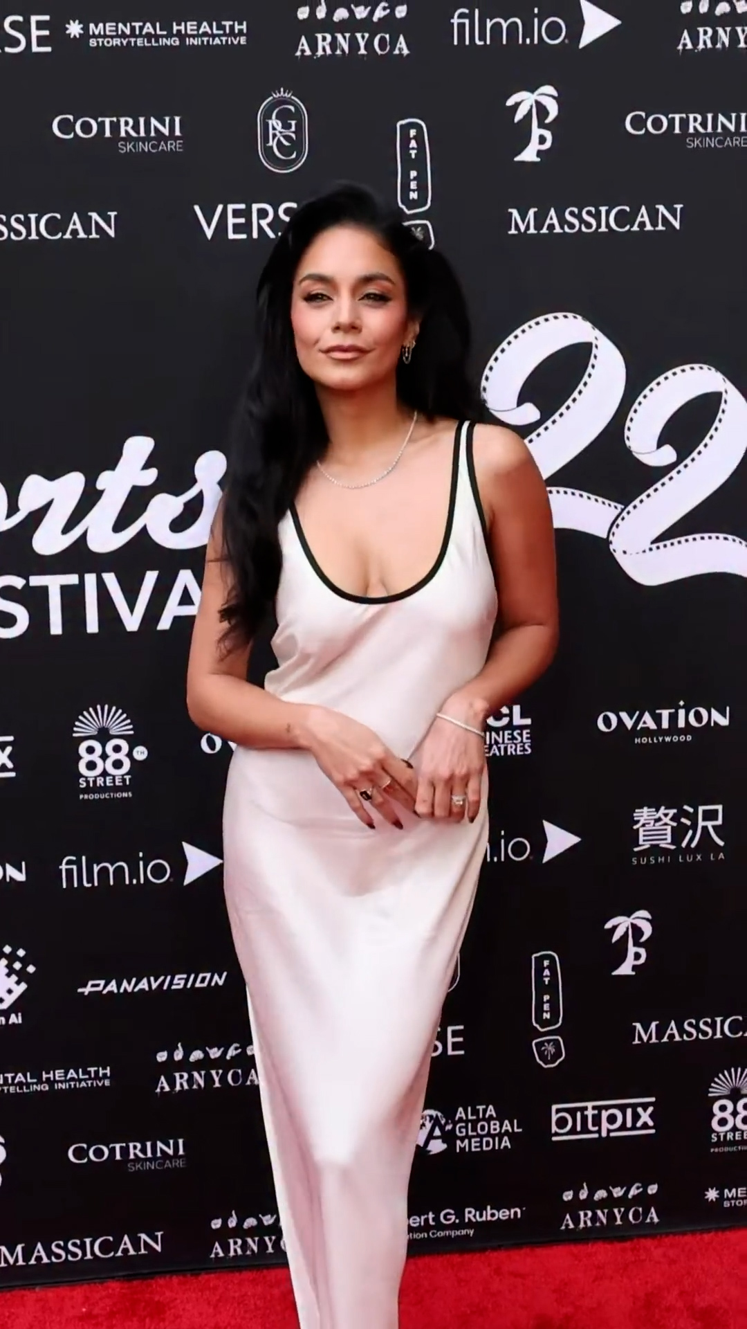 Vanessa Hudgens wearing a sleek white satin slip dress with a plunging neck on the red carpet