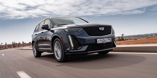 Это было еще до пандемии. Cadillac XT6 словно большой корабль плывет по руслам-улочкам Марракеша. А трафик здесь бурлит: часто рискуешь придавить внезапный скутер или задеть прогулочную карету с упряжкой зашоренных лошадей. Мы помним, что кроссовер мониторит помехи и при опасном сближении с объектом впереди может сам резко затормозить — полезная страховка. Но с такими крупными габаритами ехать в городской толчее все равно тяжело.

Создали ХТ6 по известному принципу «унификация и приумножение». Платформа и многие решения заимствованы у кроссовера XT5, величина базы у «большого брата» схожая, почти один в один. А вот общая длина отличается на 235 мм — кузов вытянут до 5 м, что позволило разместить третий ряд сидений. Самым-самым у фирмы так и остается огромный Escalade, поэтому XT6 оказался как бы заместителем главного.Передняя часть ХТ6 с эффектным технооформлением в духе концептуального седана Escala и стандартными светодиодными фарами наводит на мысли о временах, в которых автомобили Cadillac выходили за рамки общего. Смотришь анфас – колорит, стиль.

Водительское место без сюрпризов, поскольку во многом повторяет XT5. «Мультируль» с лепестками АКП, богатый информацией приборный экран, проектор на лобовое стекло, «быстродействующий» центральный тачскрин, блок климат-контроля, пульт медиасистемы на тоннеле — все это знакомо и нравится. Так же быстро подбираешь удобную посадку.Интересно, что на средний ряд можно заказать диван или два кресла, цена при этом не меняется. На тестах в Марокко машины исключительно с креслами. Оказывается, что сидеть на таком ряду не очень комфортно. Свободы сколько надо, но сами кресла узковаты и жестковаты, их спинкам не хватает глубины. Поэтому такой шестиместный вариант не выглядит лучше семиместного с диваном. На третьем ряду неожиданный простор. И важно, что «галерка» не упирается в пятую дверь, оставляя для груза объем в 357 л, то есть примерно с багажник в автомобиле гольф-класса.И мотор объемом… как будто от гольф-класса. Единственный доступный в России двигатель — это бензиновый наддувный двухлитровый агрегат, дефорсированный до налоговыгодных 200 сил. И еще выгоды ради здесь могут периодами отключаться два из четырех цилиндров. Коробка передач тоже безальтернативная — автоматическая 9-ступенчатая.Для увесистого кроссовера со снаряженной массой 2176 кг возможностей турбомотора достаточно. Да и только. Не та история, когда при разгоне автомобиль кажется легче, чем есть. Зато ускорения комфортные: двигатель хорошо отзывается на перемещения педали газа, а коробка перебирает ступени по большей части толково и плавно.

Смущает, что экономичность на поверку так себе. Расход бензина по борткомпьютеру в зависимости от манеры езды у нас разнился от восьми до пятнадцати литров. И нам не хватает подходящего богатому «Кадиллаку» звучания большого движка. В салоне или тихое благополучие, или нарастающее с ростом оборотов мерное гудение. Хотите насыщенный звук — включайте аудиосистему.На выбор предложены два исполнения ХТ6. Помимо стандартного варианта Premium Luxury можно заказать вариант Sport. У спортивного кроссовера меньше хрома и больше черного глянца, отличаются дизайном колесные диски (они у модели неизменно 20-дюймовые), в подвеске применены адаптивные амортизаторы, руль потяжелее. А еще Sport — это более сложная система полного привода. Если в стандартной схеме заднюю ось подключает одна муфта, то у Sport сзади две муфты для раздельного подключения колес.

Меню ездовых режимов начинается с базового «Тур» — передний привод с отключенным валом. Далее по списку: «AWD», несколько нервный «Спорт» и «Бездорожье». Выбираем последний и пытаемся перевалить по диагонали невысокую рыхловатую гряду, добиваясь вывешивания. Premium Luxury почти сразу зависает наглухо. А вот Sport со сложным приводом неторопливо старается преодолеть препятствие. Но на рыхлом ожидаемо пасуют шины, и туша проваливается.