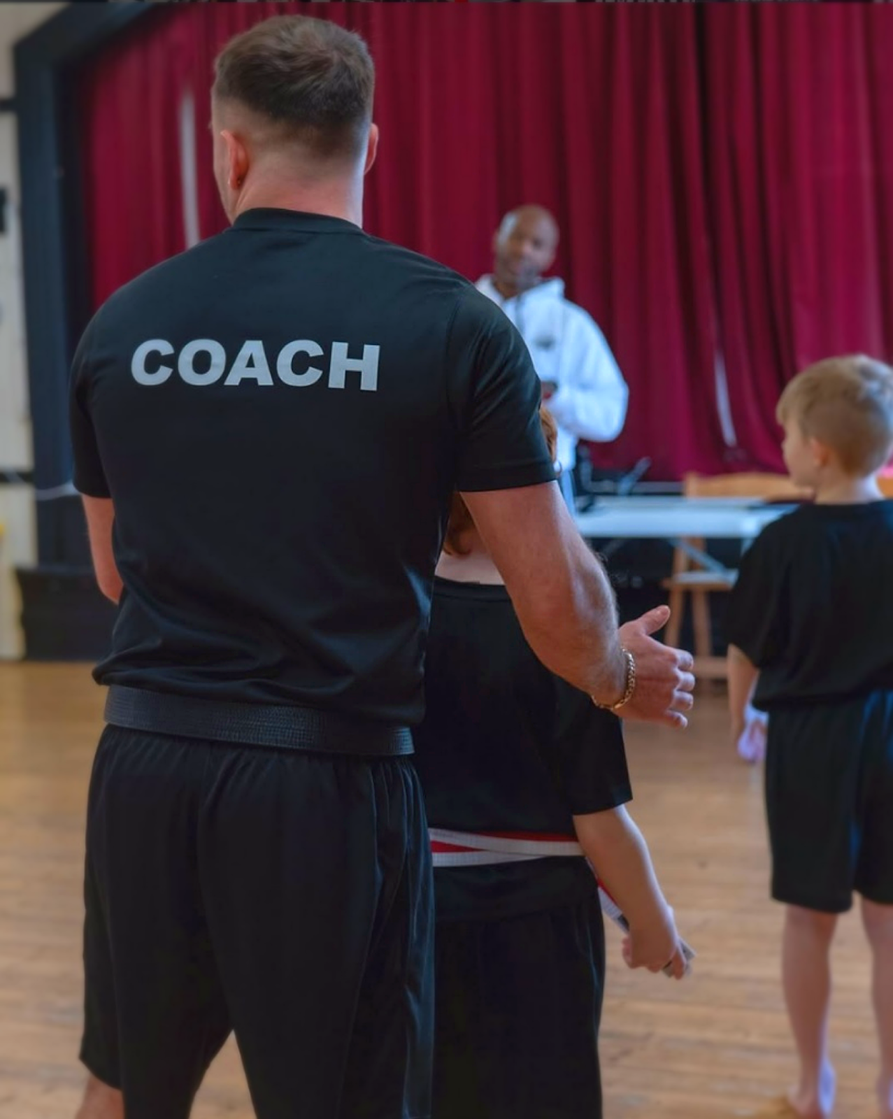 A Harris Kickboxing Academy coach working with a young student