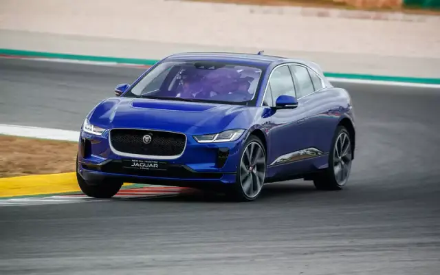 Jaguar I-Pace: никакого топлива, только электричество!
Первые впечатления от нового кроссовера Jaguar I-Pace. Третий паркетник в истории марки полностью электрический. Никаких бензиновых или даже дизельных версий не предвидится. И с точки зрения инженера новый I-Pace - чистый шедевр. А вот шедевр ли это на дороге?
Повод: новый электрический кроссовер Jaguar I-Pace.

Место действия: Португалия.

Jaguar I-Pace: никакого топлива, только электричество!
I-Pace самый «драйверский» электромобиль из всех, на которых я ездил. А их было немало.

Jaguar E-Pace: первый тест-драйв
Впечатления: успехи компании Tesla многим не дают покоя, и все больше производителей выкатывают свои электрокары. Разродился и Ягуар, который лишь недавно представил свой первый в истории марки кроссовер. И вот, пожалуйста — I-Pace. Это уже третий паркетник в линейке. Но не простой, а электрический! Хотя своим силуэтом он скорее напоминает купе. Вот она, красота проектирования электромобиля — отсутствие традиционных агрегатов, часто задающих компоновку, развязывает руки инженерам. В итоге относительно компактный кроссовер обладает внушительной колесной базой в три метра. Колеса расставлены практически по углам. И если на задних рядах это не особо сказалось — запас пространства грандиозным не назовешь, то на ходовых возможностях минимальные свесы сказались самым положительным образом. Да, будущее наступило — мы говорим об отточенной управляемости у электромобиля.
Jaguar I-Pace: никакого топлива, только электричество!
Электрическую сущность Ягуара выдают лишь непривычные приборы виртуальной панели. Почти все функции отданы на откуп сенсорным экранам. Но и физическим кнопкам место все же нашлось.
Jaguar I-Pace: никакого топлива, только электричество!При внушительной колесной базе задние места нельзя назвать образцом простора. Места для ног рослых пассажиров при посадке «за собой» впритык. Как и запаса воздуха над головой.
На пользу управляемости пошел и низкий центр тяжести. Батарея общим весом в 650 кг расположена по всей площади пола, очень низко. Емкость в 90 кВт.ч обеспечивает очень солидный запас хода в 480 км. В теории. На практике он, конечно, меньше, особенно если не стесняться давить на педаль газа… простите, акселератора. Но все равно можно легко проехать больше 300 км без подзарядки. Результат более чем достойный, а давить на педаль хочется. 400 электрических сил обеспечили Ай-Пэйсу не только впечатляющую динамику разгона в 5 секунд до первой сотни, но и совершенно сумасшедшую эластичность. Ведь прелесть электромотора в том, что крутящий момент у него постоянный!

Jaguar I-Pace: никакого топлива, только электричество!
В заявленные 650 литров объема багажника верится с трудом. Даже с учетом подполья и небольшого багажного отсека «под капотом». Проверим, когда машина попадет к нам в сравнительный тест.
I-Pace стал не только первым кроссовером на электротяге в истории Ягуара, но и первым кроссовером с пневмоподвеской и возможностью регулировки дорожного просвета. Передняя подвеска позаимствована у модели F-Type, задняя — переработанная от F-Pace. В стандартном положении клиренс Ай-Пэйся составил 155 мм, а в верхнем — 205, что для такого кроссовера весьма прилично. Сказалось ли это на проходимости? Еще как! Да и на гоночном треке, куда мы отправились во время теста, «электрокошка» оказалась очень проворной.

Jaguar I-Pace: никакого топлива, только электричество!650-килограммовая батарея состоит из 36 модулей по 12 ячеек и пристроилась в полу в специальной раме. Энергоемкость 90 кВт*ч. Заявленный запас хода — 480 км.
Перспективы: завод в Граце, где будет производиться I-Pace, готов выпускать аж до 30 тысяч машин в год. Для электромобиля это очень много. Рассчитывать на какие-то грандиозные показатели продаж ягуаровцам не стоит, хотя потрепать нервы Тесле новый i-Pace имеет все шансы.