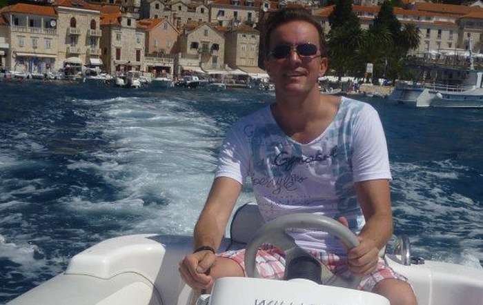 Richard Bertossa on a boat in front of a coastal town