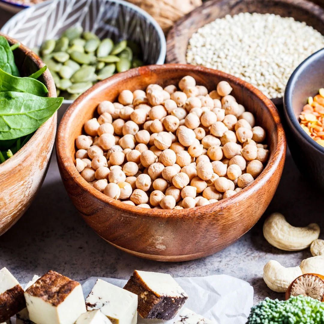 Assortment of plant proteins including chickpeas, lentils, beans, tofu, nuts and seeds, illustrating the diversity of available sources.