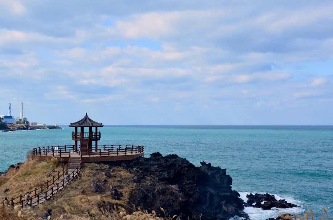 View of Hyeopjae Beach on Jeju Island's west coast showing clear turquoise water with Biyangdo island visible in the background