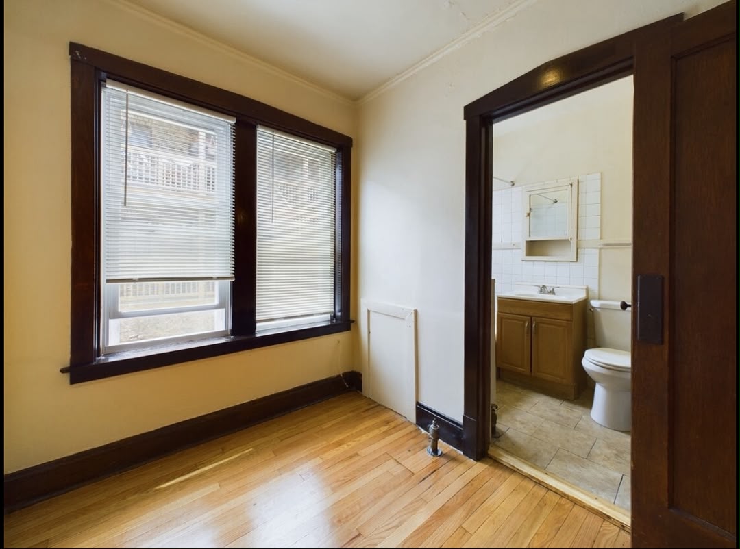 Apartment room with hardwood floor and bathroom access