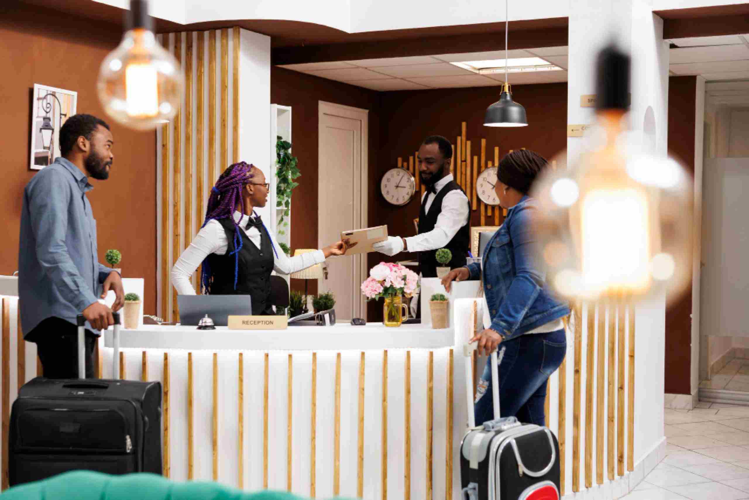An image showing the Front desk in a Hotel and guests checking in.