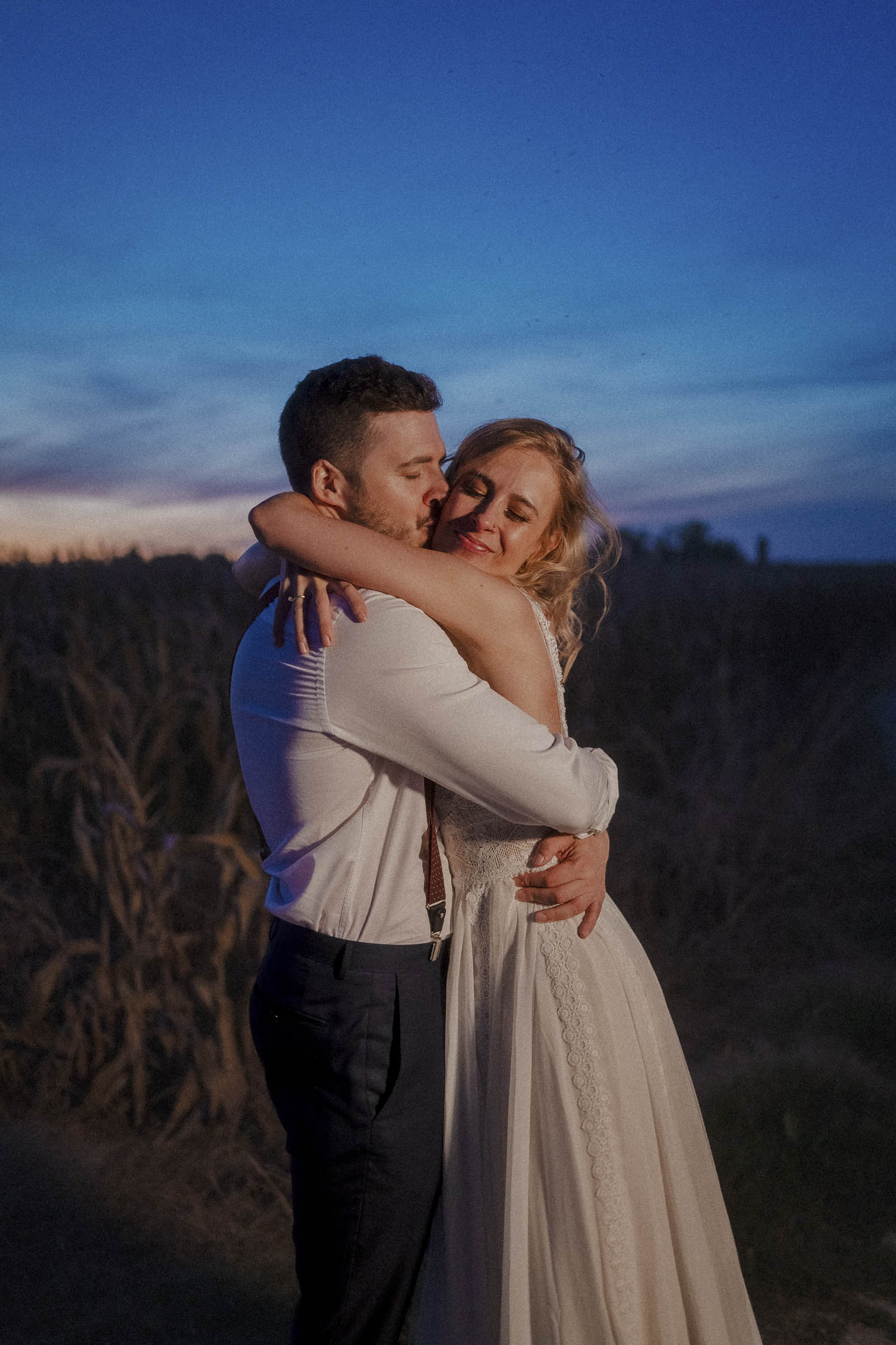 Retrato romántico de una pareja durante su postboda en Madrid entre campos al anochecer