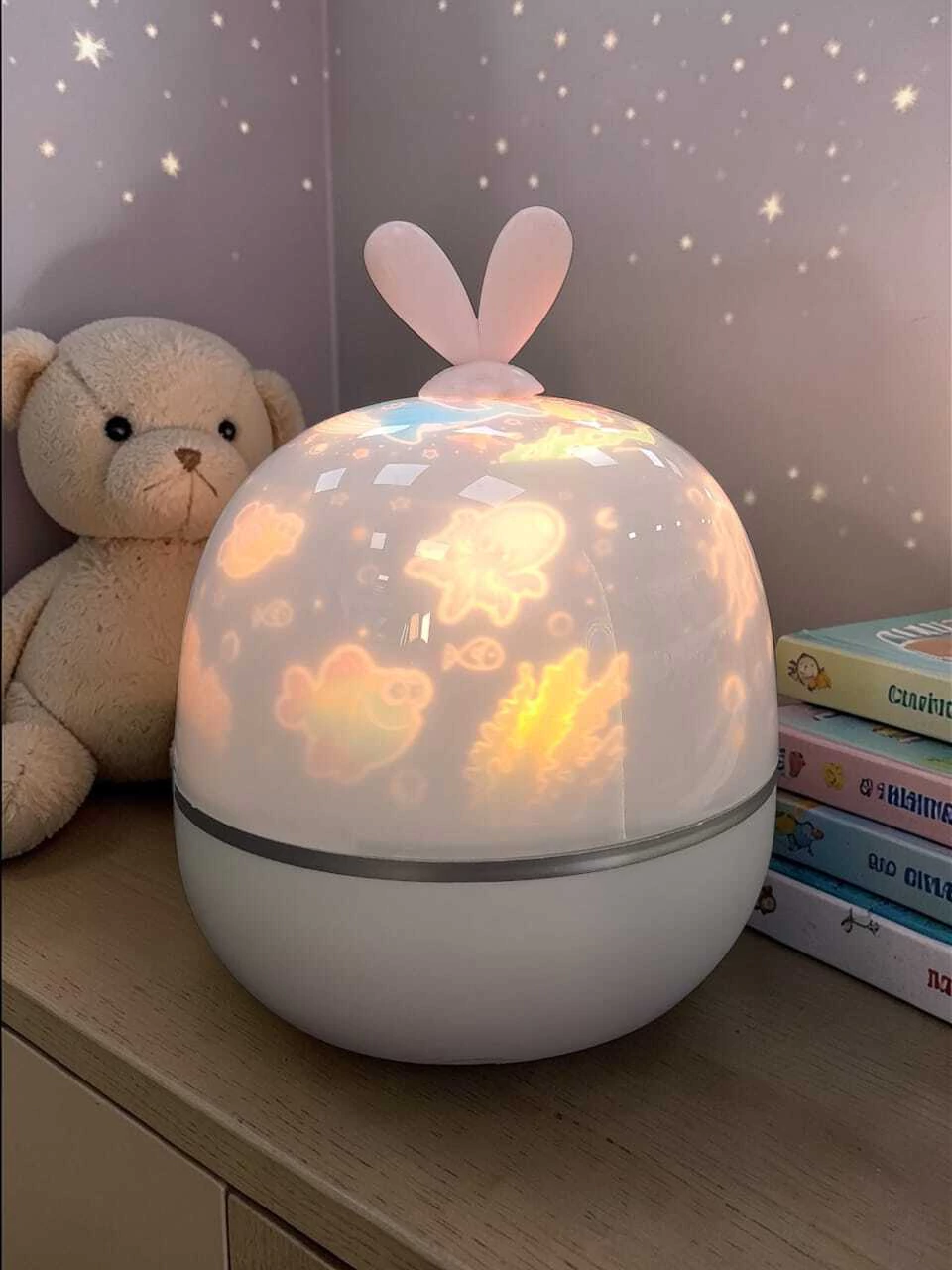 Proyector velador infantil con orejitas proyectando im&aacute;genes y estrellas en una habitaci&oacute;n