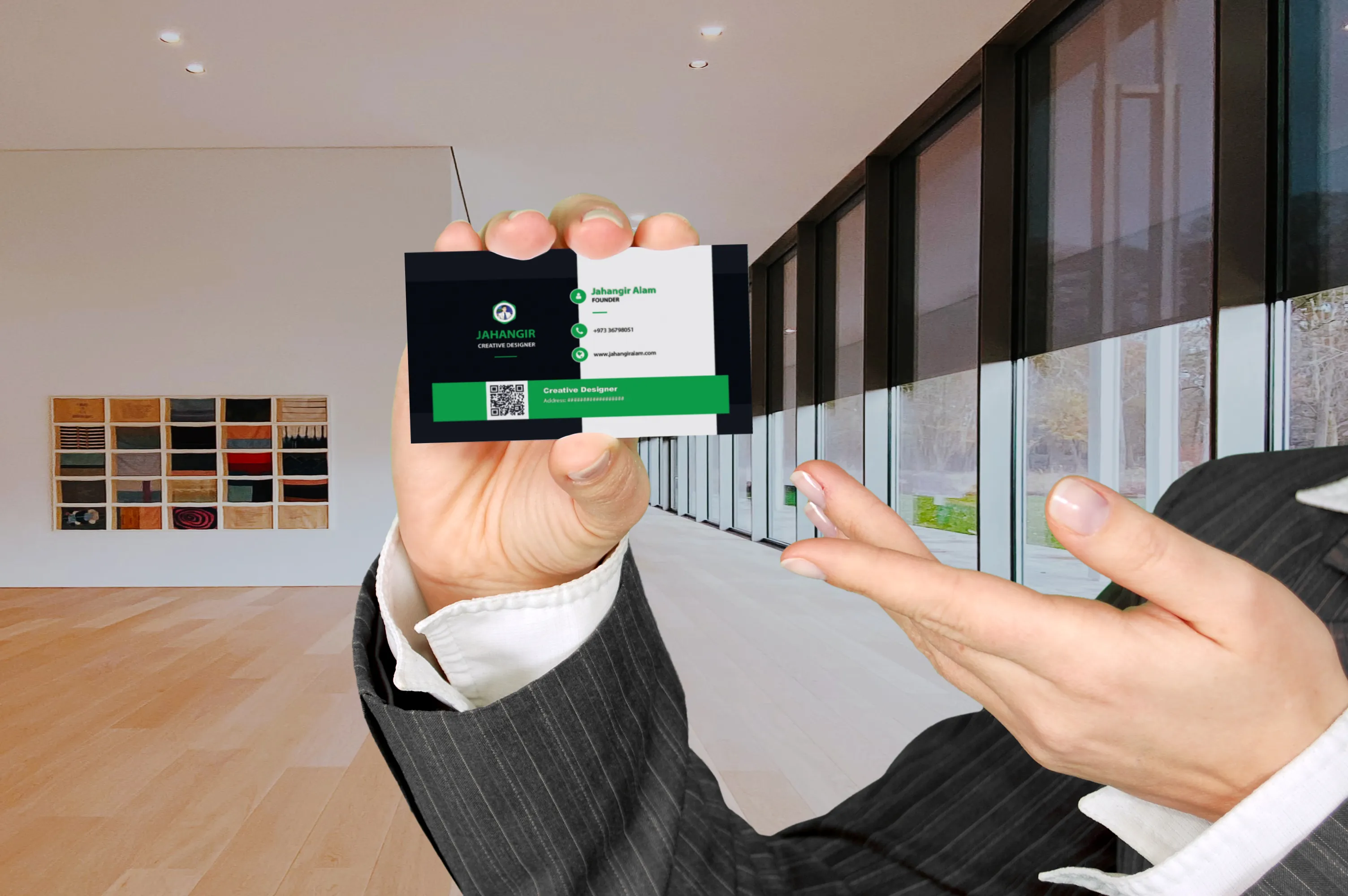 A person wearing a pinstripe suit holding out a black and green business card for Jahangir Alam in a modern office hallway. Jahangir