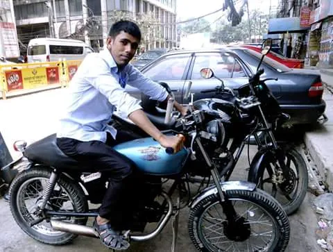 Young man sitting on a light blue custom motorcycle parked on an urban city street. Jahangir