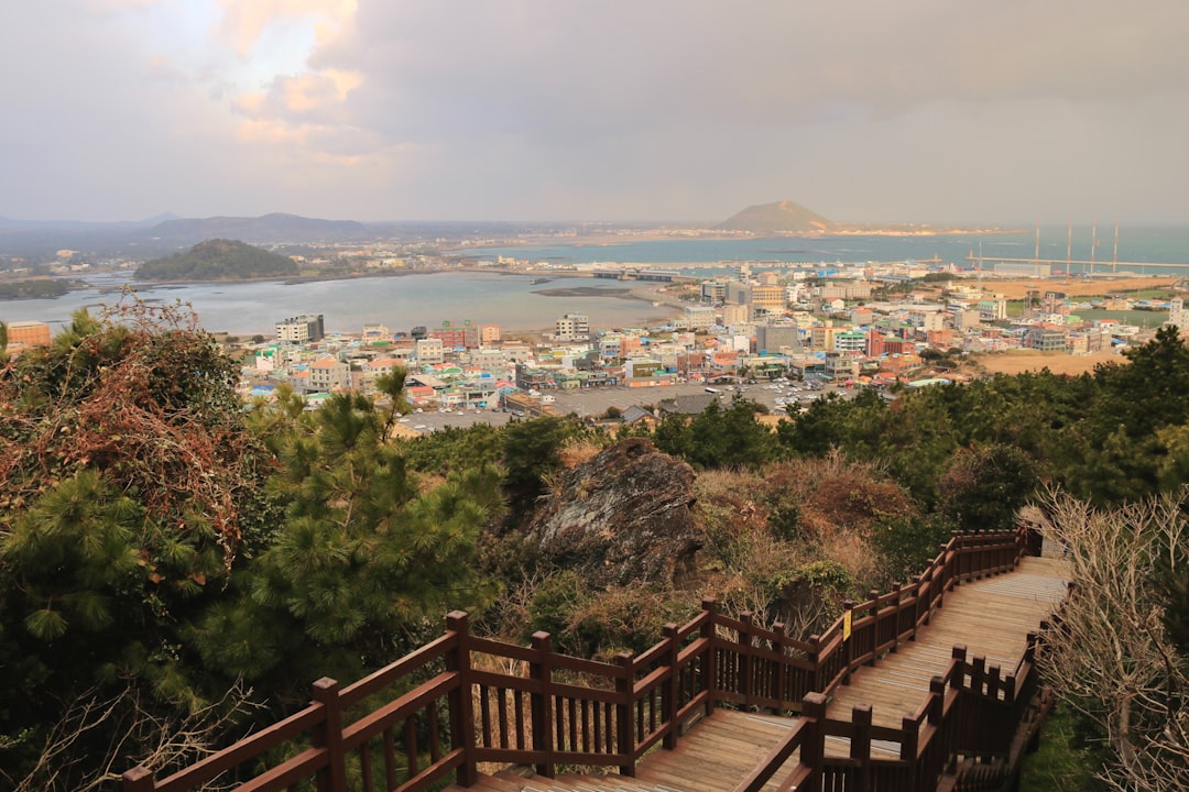 Hilltop path view over Seongsan-eup town with volcanic peak of Seongsan Ilchulbong visible on the east coast of Jeju Island, entrance fee ₩5,000 as of 2026