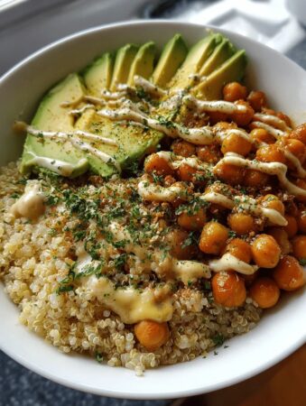 A colorful chickpea and quinoa bowl with fresh vegetables and zesty dressing, served as a protein-packed, healthy meal option.