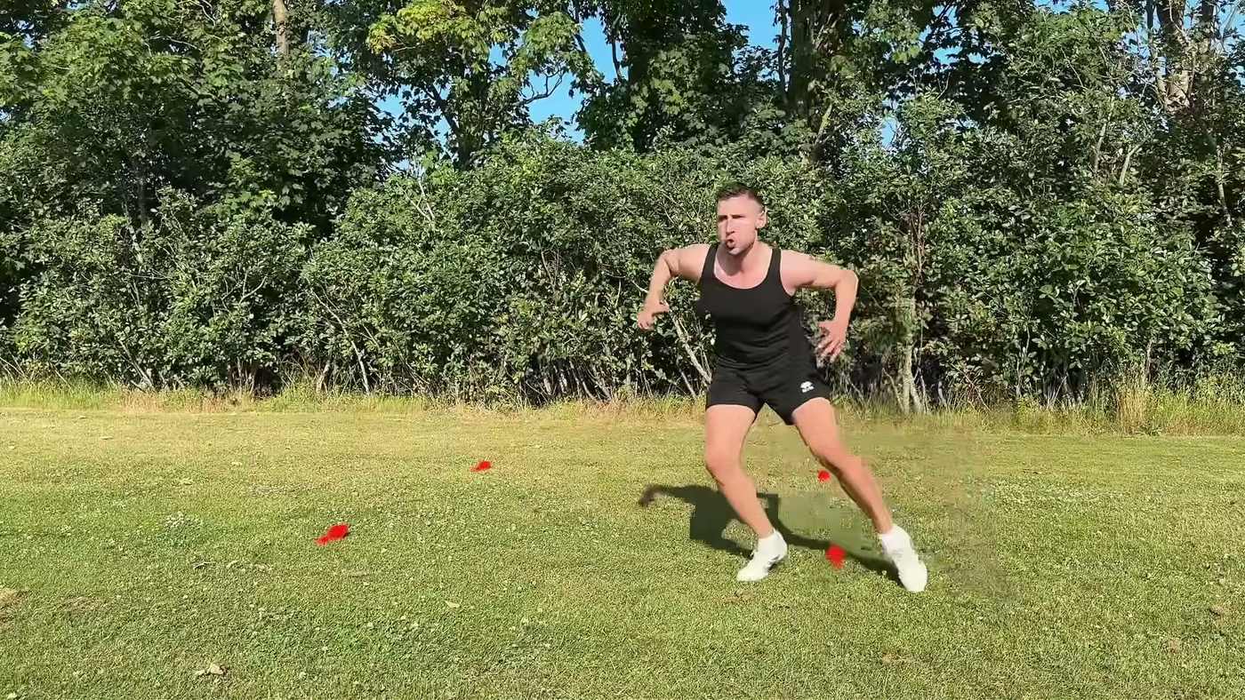 Goalkeeper side-stepping around a small square of four cones on an empty pitch