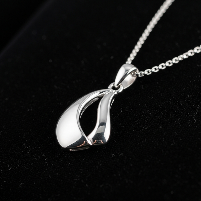 O imagine macro, elegantă și minimalistă, a unui colier din argint 925 fin lucrat, așezat pe o suprafață de catifea neagră. Lumina de studio accentuează perfect luciul metalului și detaliile fine ale pandantivului, creând reflexii subtile. Focusul este pe calitatea impecabilă și designul atemporal al bijuteriei.