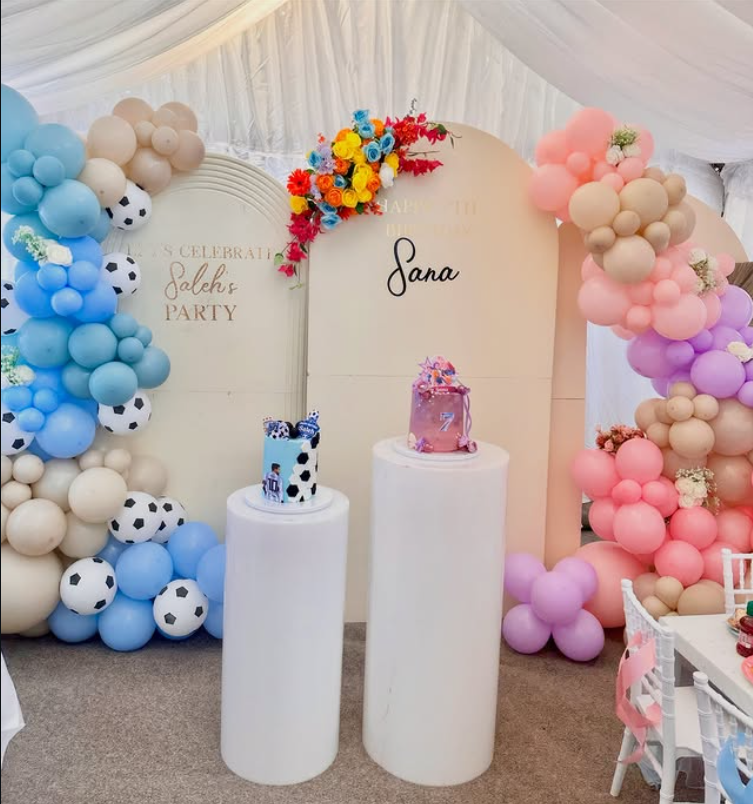 Multi-panel custom pastel arch backdrops with colorful flowers, balloon garlands, and pedestals