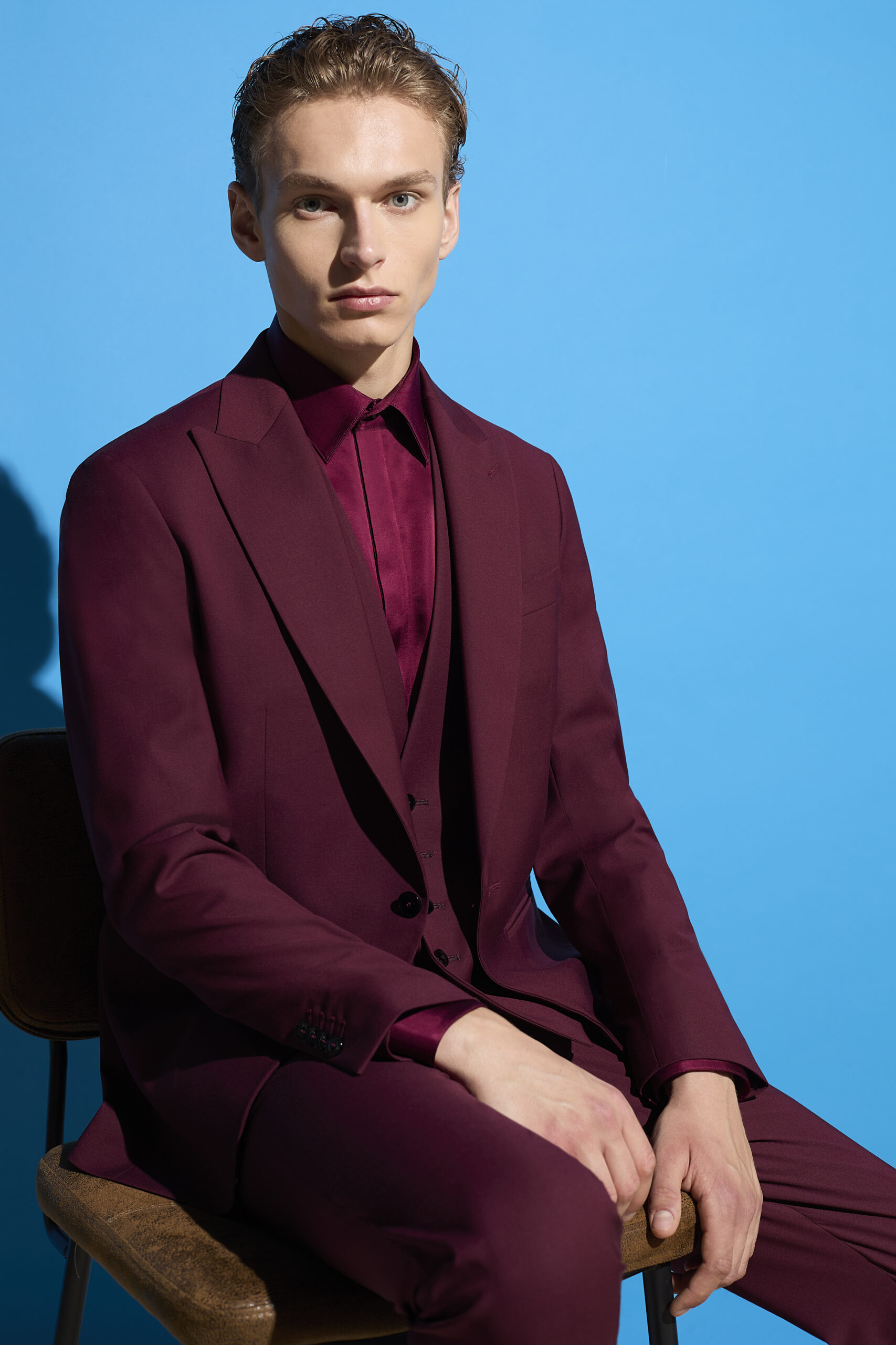 Pignatelli SS26, il rebranding a Milano Moda Uomo ragazzo seduto con completo elegante sartoriale maschile bordeaux