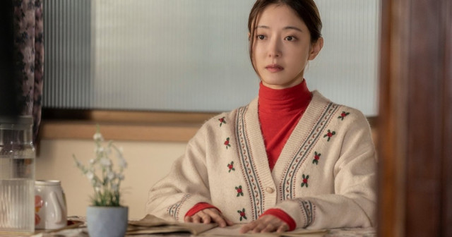 여전히 찬란하게 스틸컷, 붉은 터틀넥에 카디건을 입은 젊은 여성이 식탁에 앉아 있는 장면