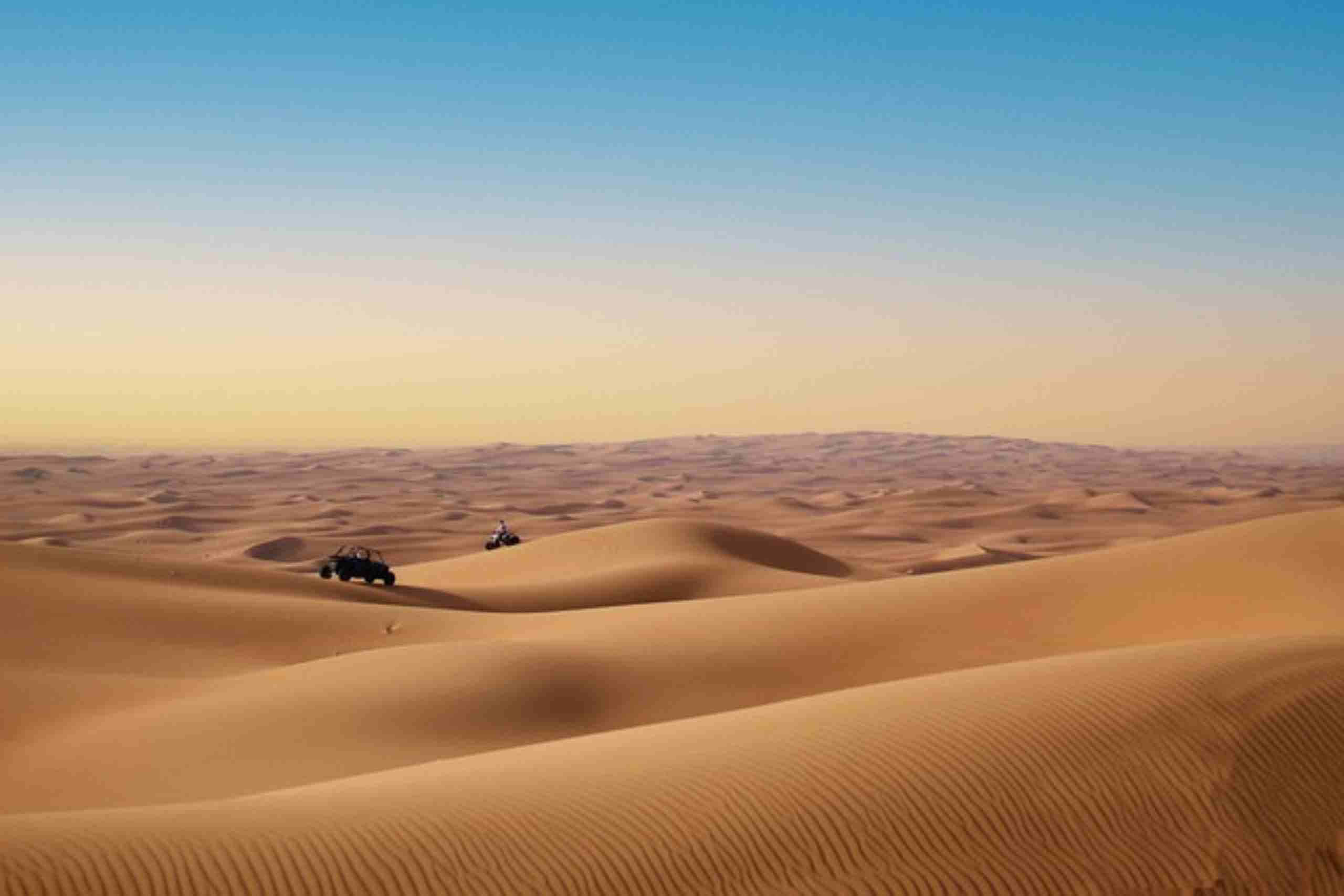 An image showing a desert with sand dunes and motorists traversing the golden landscape depicting the Nigerian sand dunes.