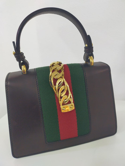 "The bag is high on style with its top handle design and is breathtaking to look at.
It's crafted in Italy with the hallmark red and green Web-striped centre panel that's layered with a gold-tone metal chain and buckle plaques, then finished with two interchangeable shoulder straps: one crafted from  leather and the other fashioned from twisted-rope in red, off-white, and navy. . It is complete with a detachable shoulder sling."