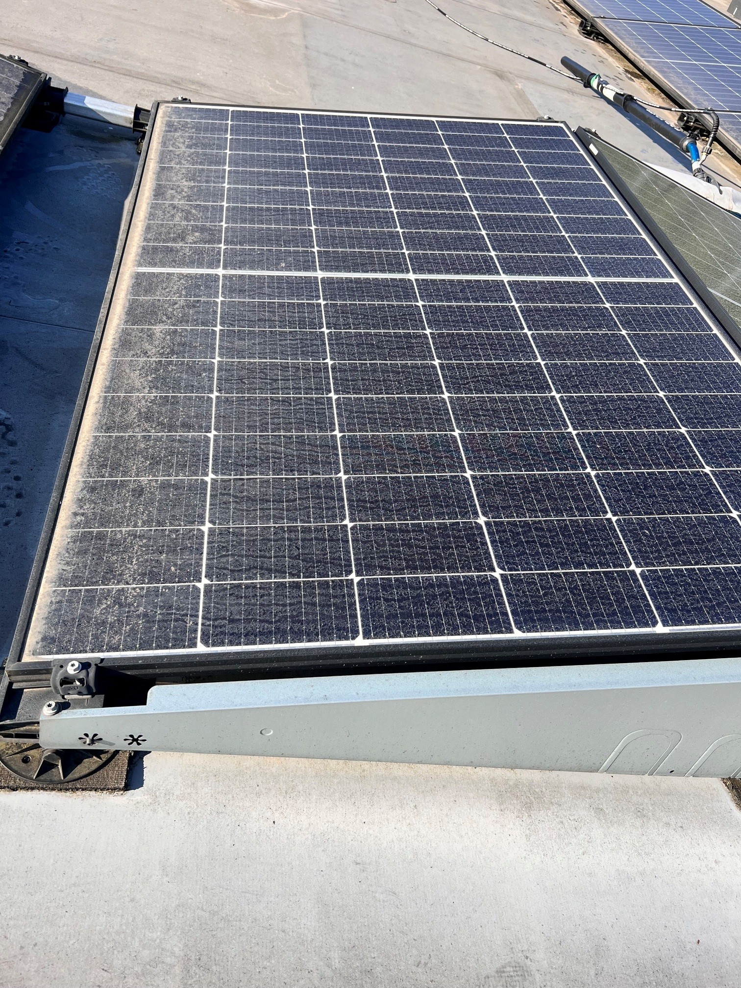 Großes Gewerbedach in Lindlar mit langen PV-Modulreihen – 347-kWp-Anlage vor der Reinigung, im Hintergrund Waldrand