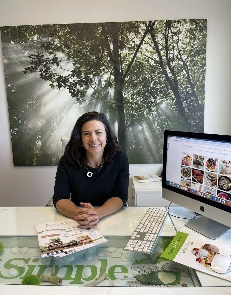 Diététiste-nutritionniste clinicienne discutant avec un patient devant un écran affichant des données nutritionnelles, illustrant l'intégration de l'IA en nutrition.