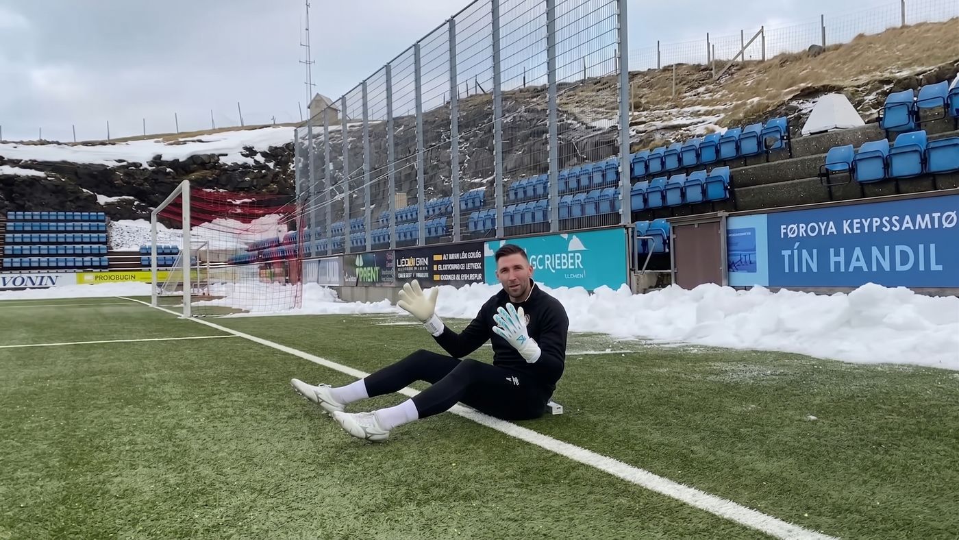 Goalkeeper sitting on the grass with a ball in his hands at the top of a sit-up