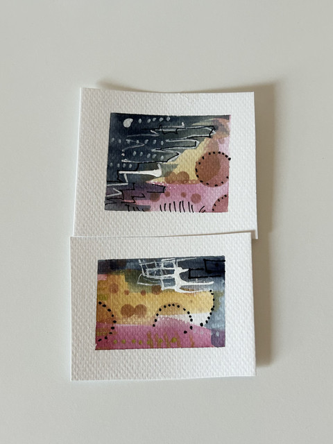 Two tiny paintings with matching blue, yellow and pink backgrounds. With gold circles, black dots and white lines for added details.