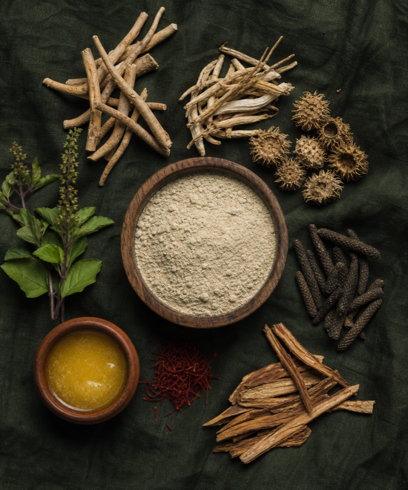 Ayurvedic herbs and weight gainer powder arranged on forest green linen