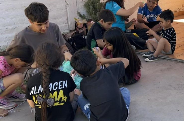 ni&ntilde;os jugando con voluntarios de Huellas tejiendo y haciendo enredaderas