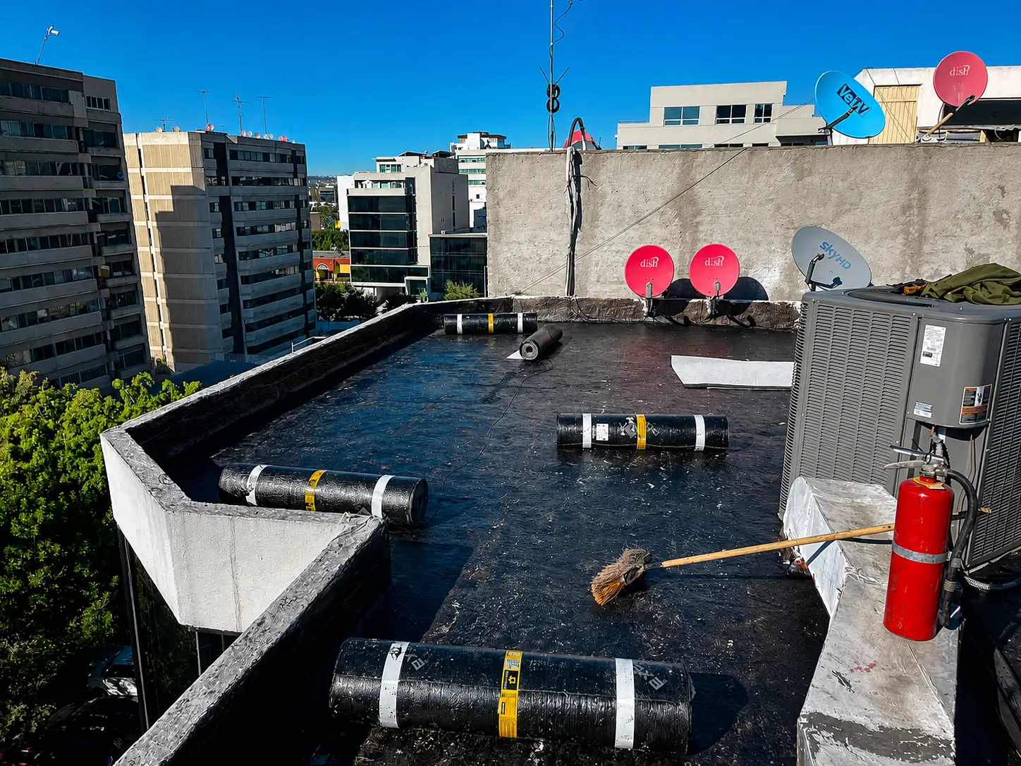 Azotea de edificio con imprimación completa y rollos de manto distribuidos por paños
