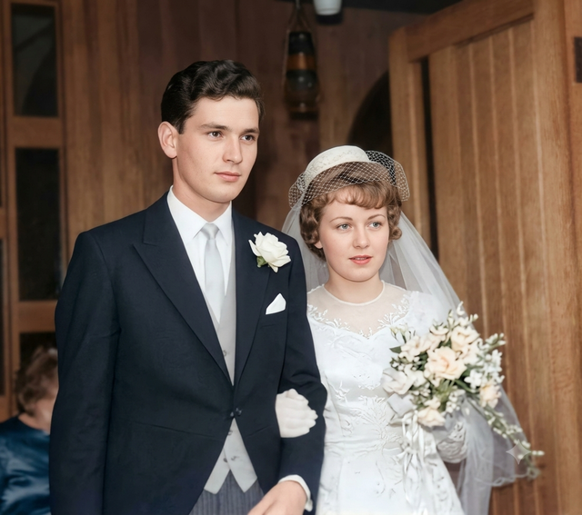 Prompt:
A hyper-realistic, 4K resolution color photograph of the wedding couple from image_0.png, presented as a flawless, borderless print. The severe physical damage, creasing, tears, and cyan/blue fading are entirely removed, revealing a pristine scene. The central large lens flare is gone. The focus is crystal clear on the main couple, with a beautifully rendered, natural, 3D-like photographic depth of field, rendering the background (windows, wood paneling, and the extra person) softly blurred. Every detail of the original couple’s faces and expressions is maintained with extreme precision, acting as a rigid geometric template; their specific features and gaze directions are preserved perfectly. The groom is wearing a dark, tailored suit (black or charcoal) with a white rose boutonnière and a white pocket square, his dark hair is neat, and his face is clear. The bride, in her white dress with delicate lace and embroidery, and her unique headpiece (like a small pillbox with a net and veil) is perfectly restored. Her expression is maintained. The bouquet of flowers is detailed and distinct. All physical artifacts, water damage, and color distortions are corrected to natural, lifelike skin tones and materials (wood, fabric). The lighting is soft and flattering, from an ideal professional source. The composition and framing are identical to image_0.png, with the third person in the lower-left and the hanging object above. The overall appearance is that of a professional portrait taken with a high-end digital camera under ideal conditions, with lifelike textures and details.