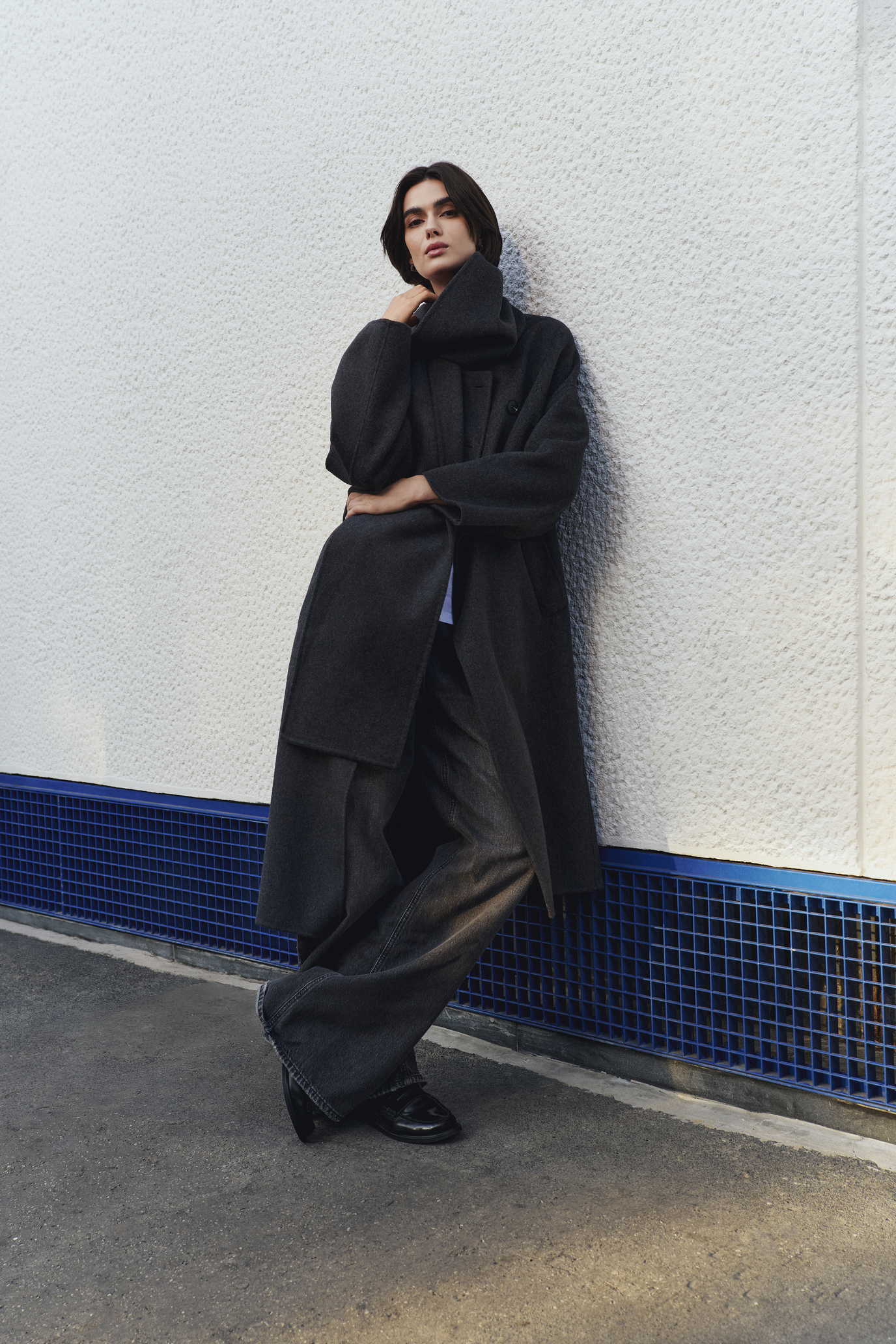 Coin Contemporary – cappotto oversize grigio Modella posa con cappotto oversize grigio e pantaloni ampi della collezione Coin Contemporary