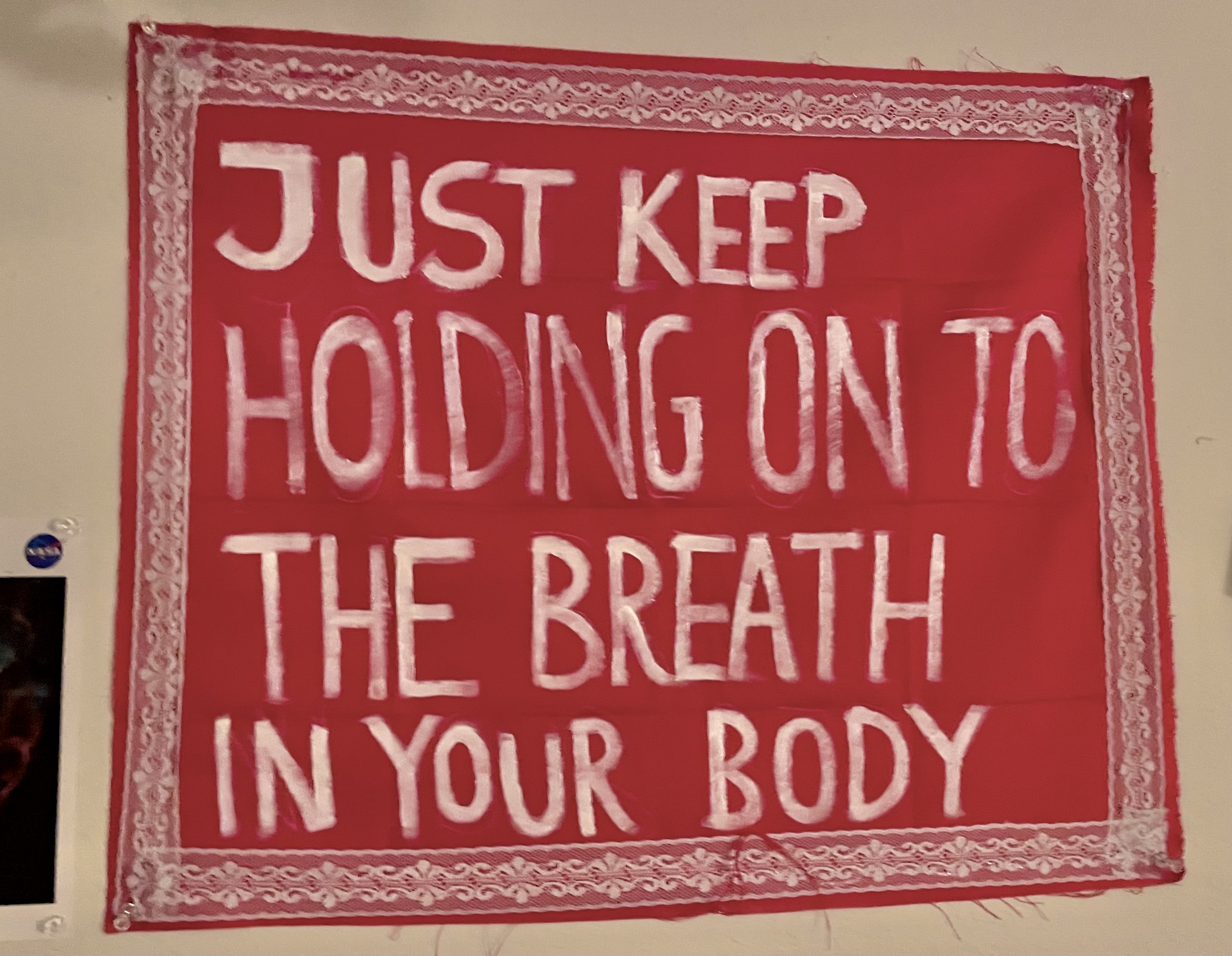 red tapestry that says 'just keep holding on to the breath in your body'