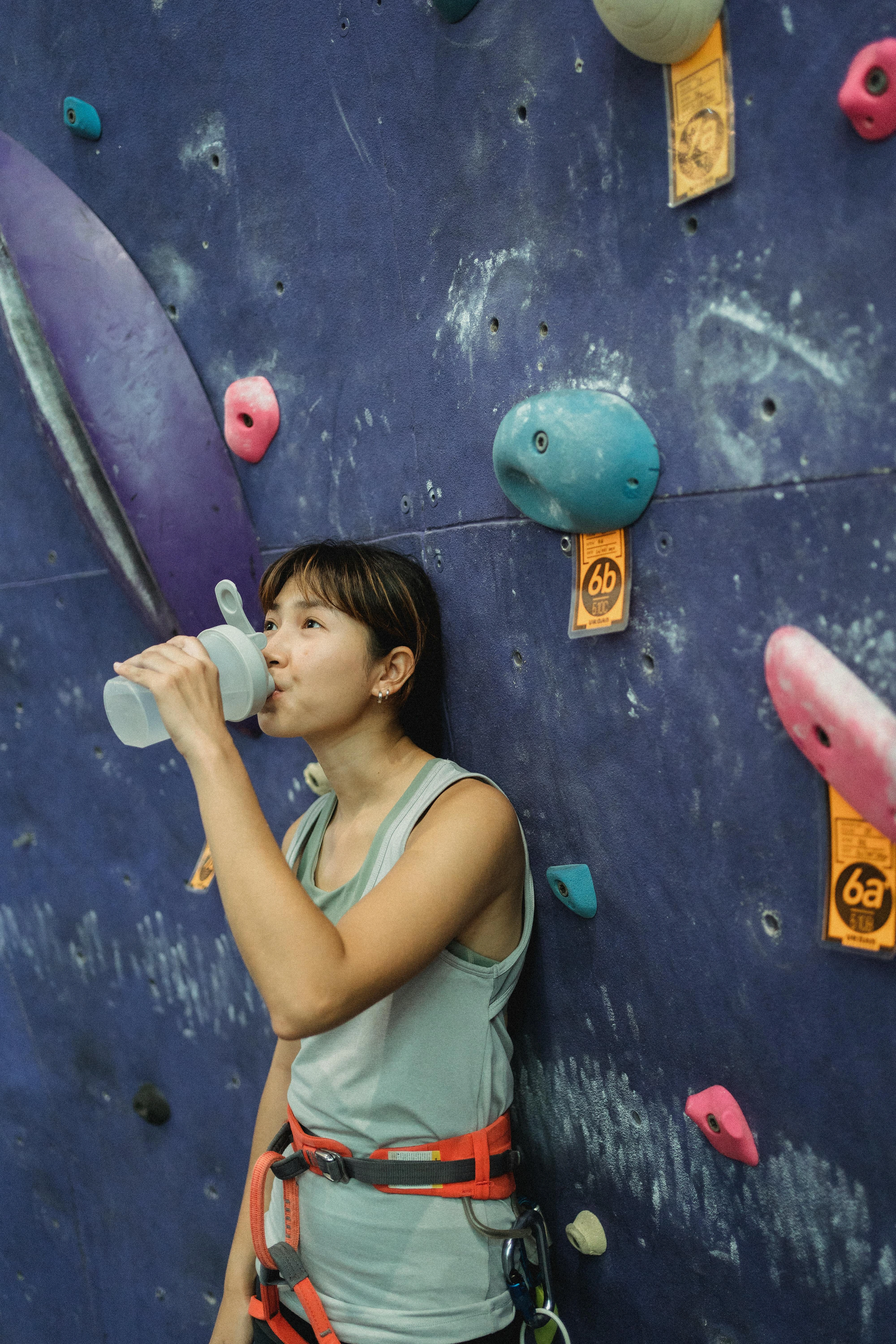 Grimpeur tenant une bouteille d'eau avec des électrolytes, soulignant l'importance de l'hydratation pendant l'escalade.