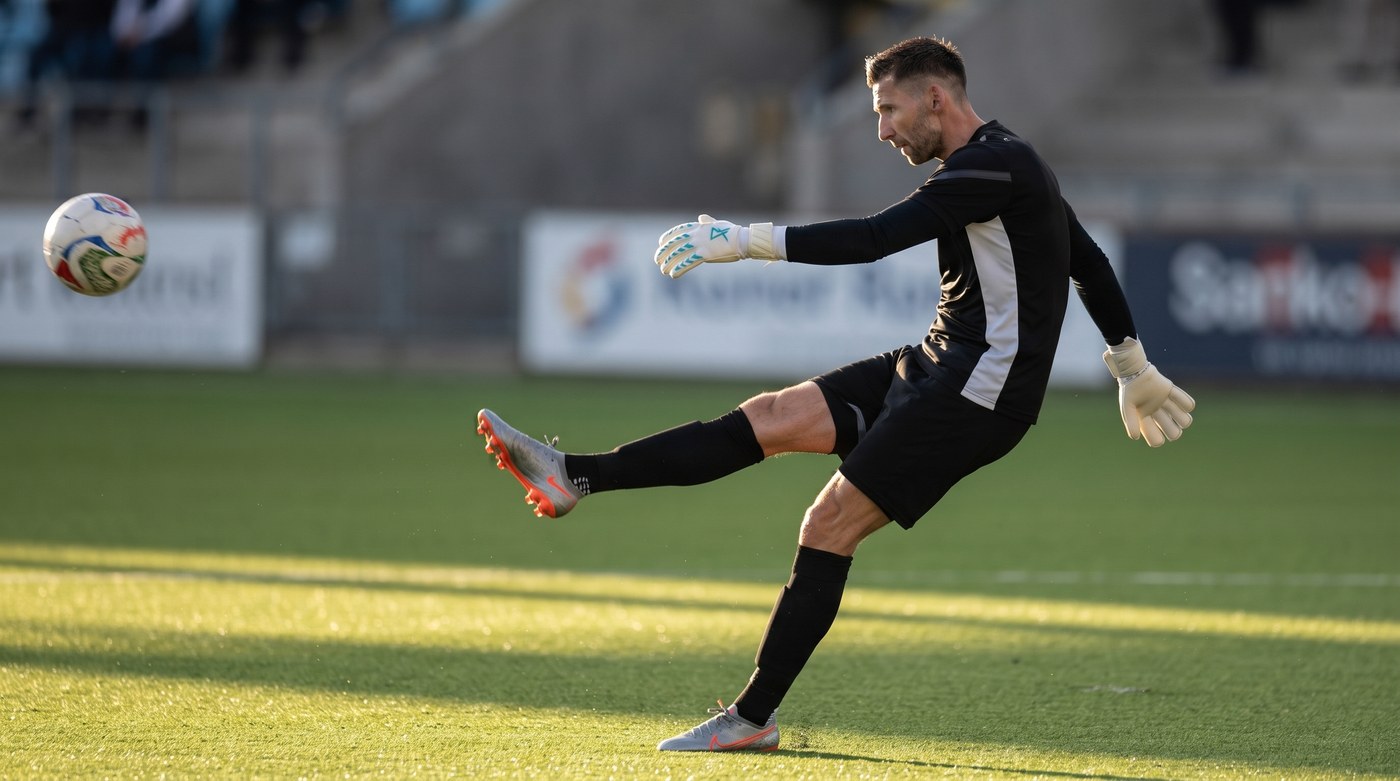 Goalkeeper at the top of a long kick, standing leg locked, kicking leg swung right through