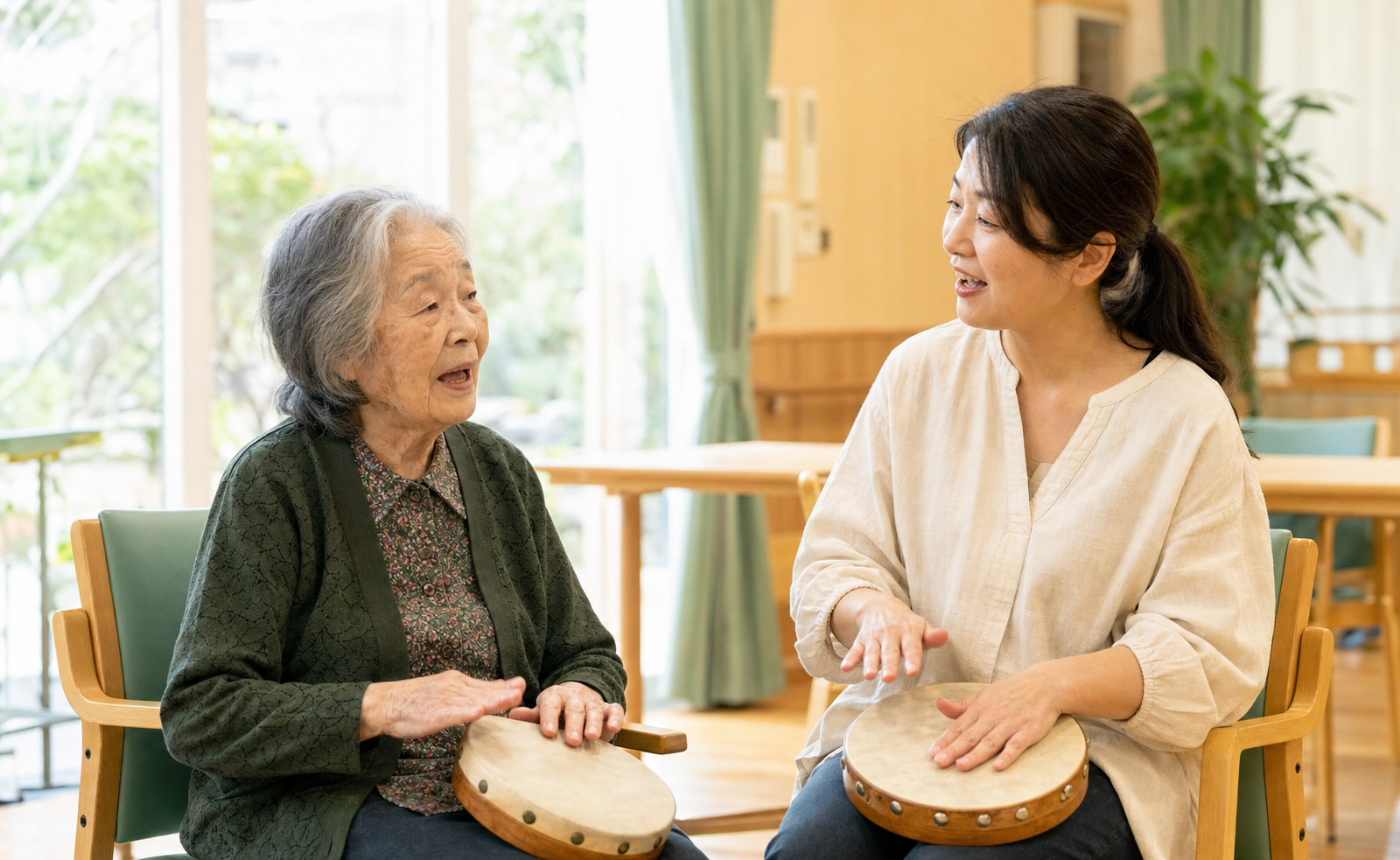 高齢女性と音楽療法の支援者が一緒に歌いながら太鼓を鳴らす様子
