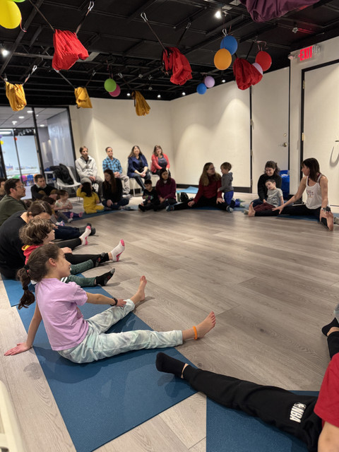 Kids and parents sitting in a circle on yoga mats at a Yoga@Play birthday party