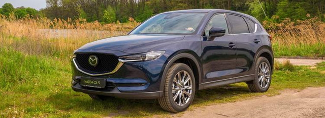 Кроссовер Mazda CX-5, который в своем классе уже долго остается одним из лидеров, в последнее время получил несколько сильных соперников – очередные поколения Toyota RAV4 и Honda CR-V. И не только среди конкурентов – весной появилась немного меньшая "сестра" Mazda CX-30, которая внешне очень похожа на СХ-5, а по интерьеру и технологиям стремится перегнать старшую модель.Мягко и стильно
Внешне отличить обновленную Mazda CX-5 от модели предыдущих лет очень сложно – различий практически нет. Разве что передний логотип на топ-комплектации стал плоским. В нем скрываются радары систем.LED-фары и LED-противотуманки на Mazda CX-5 устанавливаются с минимальной комплектацией, а вот задние фонари светодиодные только на полноприводных версиях. Если очень внимательно изучать обновленную модель внешне, то на топ-версии, как у нас на тесте, можно увидеть другой дизайн 19-дюймовых колесных дисков и камеры обзора системы 360 градусов – до недавнего времени их на CX-5 не было.

В салоне отличий гораздо больше, хотя они и не бросаются в глаза. Во-первых, в комплектации ТОР появилась обивка сидений и элементов салона кожей наппа – это изысканный мягкий материал, который ранее был доступен только в премиум-брендах. Эти сидения получили еще и вентиляцию, хотя их форма не изменилась. На дверях и перед передним пассажиром – отделка шпоном со структурой дерева – не только внешне, но и на ощупь. Потолок и стойки – черного цвета, безрамочное зеркало заднего вида... Стало действительно.Центральный дисплей на консоли увеличился в размерах, но только на 1 дюйм: вместо 7" в прошлогодней версии он теперь 8". Без линейки не заметишь. Но если к нему подсоединить смартфон, то на экране машины появятся иконки программ телефона – системы Apple Car Play и Android Auto работают во всех версиях CX-5. А вот система обзора 360 градусов на этом дисплее могла быть и лучше. По крайней мере, у "младшей" сестры Mazda CX-30 качество картинки на порядок выше. Здесь изображение дает разве что приблизительное представление "где я", а вот детали заметить трудно.

Японцы также умело замаскировали еще один дисплей – на панели приборов. На первый взгляд там ничего не изменилось – круглый циферблат и белые циферки на темном фоне. Но на самом деле в центре панельки – дисплей, который в консервативном стиле Mazda показывает почти те же показатели, что и раньше. И только когда включаешь зажигание, он выдает себя надписью CX-5.Первые же метры движения в обновленной Mazda CX-5 2020 года дают четкое понимание: шумоизоляция здесь стала еще лучше, хотя в новом кузове этот показатель уже был на высоком уровне. Традиционно для “Мазды” хорошо ощущается басок двигателя при разгоне, а вот звуки дороги и ветра не донимают. Также комфортнее стало и пассажирам сзади – на трассе разговаривать с ними можно, не повышая голос.

Подвеска заслуживает комплиментов – машина проходит неровности мягко и упруго, не допускает громких или глубоких ударов. При этом управляемость на высоте – как мы уже привыкли на Mazda CX-5. В обновленной модели установлена ​​модернизированная система G-Vectoring Control+, которая следит за идеальными траекториями на поворотах. А вот к тормозам надо привыкать – перед самой остановкой их хочется дожимать сильнее.Багажник удобный, а шторка очень удобно открывается вместе с задней дверкой. В украинских версиях, как и в европейских, уже нет запасного колеса – лишь набор для ремонта.

Быть в тонусе
Все модели "Мазды" ежегодно получат обновления, которые на первый взгляд мало заметны. Однако постоянные усовершенствования каждый раз делают эти японские машины более конкурентоспособными и современными, а главные преимущества в виде яркого дизайна и премиум-направленности в комфорте никуда не исчезают.

Набор усовершенствований, которые получила Mazda CX-5 в 2020 году, тоже нельзя назвать революционными, однако сделали ее еще более современной и комфортной. И пусть более молодые модели "прижимают", бестселлер бренда всегда будет иметь для них достойный ответ.

Автор: Сергей Матусяк
Фото: Андрей