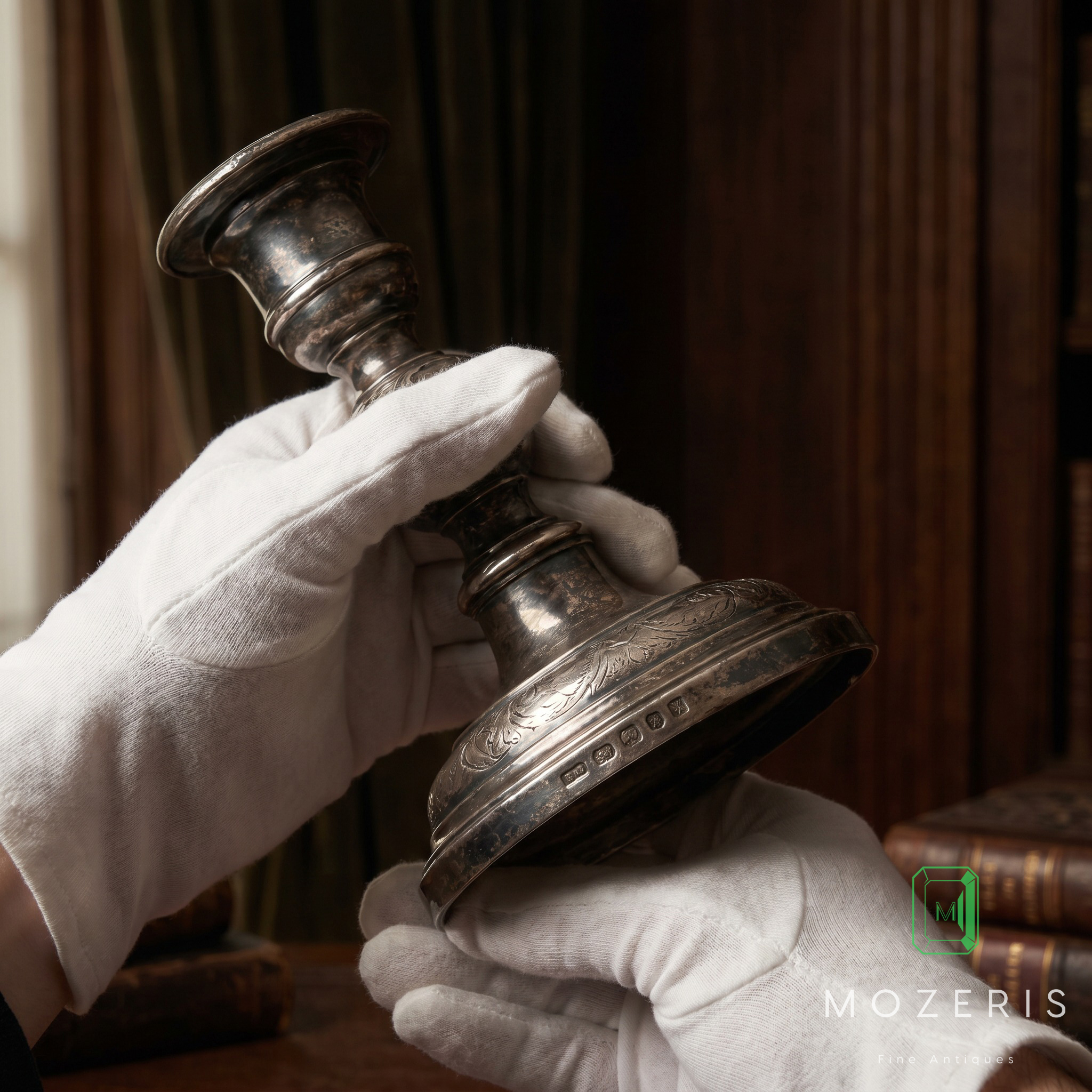 Antique silver candlestick being examined by specialist