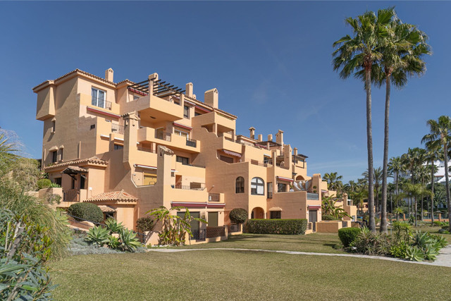 Modern Mediterranean-style apartments in Costa del Sol with landscaped gardens and palm trees, ideal for international property buyers considering real estate investment in Spain.