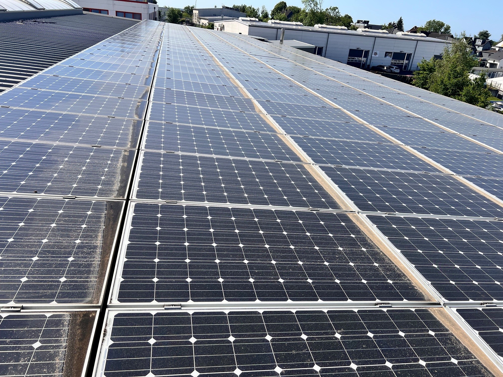 Seitliche Detailaufnahme der verschmutzten Solarmodule auf dem Industriedach in Bergisch Gladbach vor der Reinigung