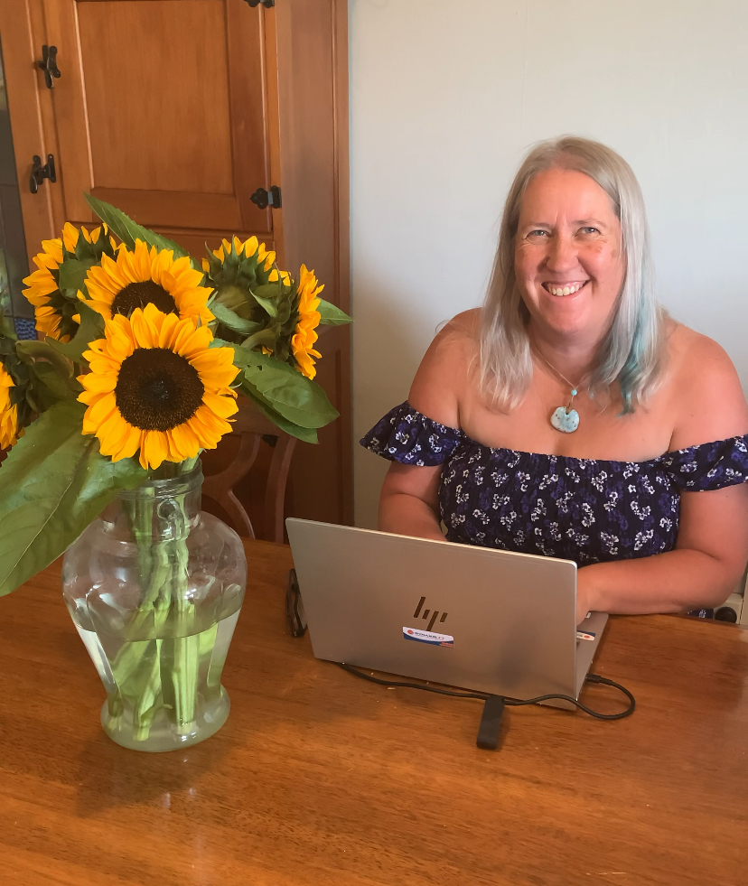 Donna working at her laptop with sunflowers beside her