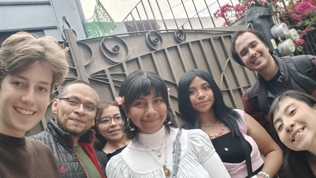 Grupo de j&oacute;venes pasantes sonriendo juntos en la entrada de una instituci&oacute;n social